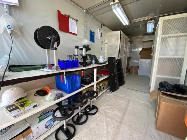 Shelving with consumables and a hose reel inside the site cabin