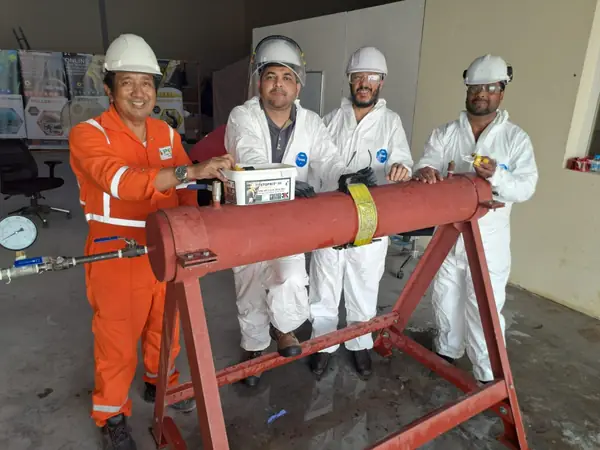 Team around a pipe test section on a stand, with a pressure gauge fitted