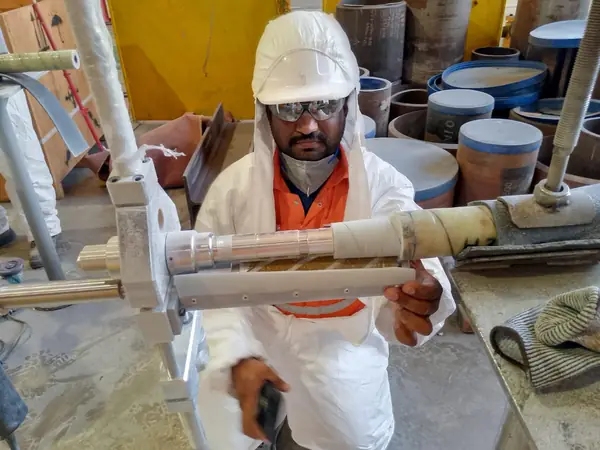 Technician holding a pipe test piece with composite wrap applied
