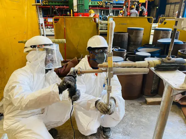 Technicians preparing a composite wrap on a pipe test piece in the workshop