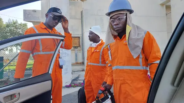 Crew members in orange coveralls beside a vehicle