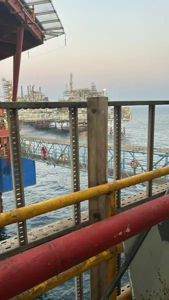 Red pipe on an offshore platform, with another platform in the distance
