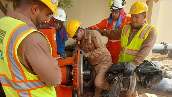 Crew in hi-vis vests working at a pipe flange