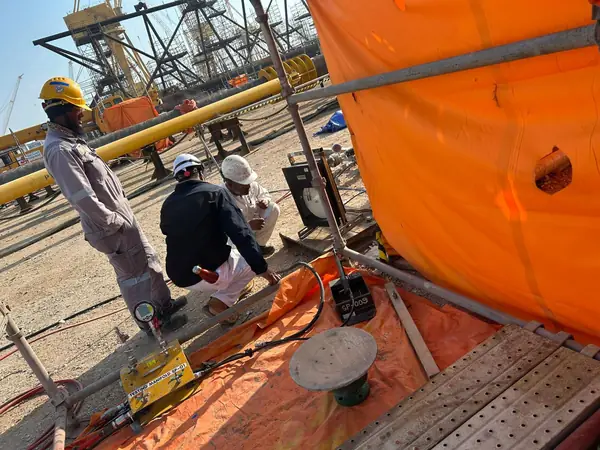 Crew working beside a large orange vessel on site
