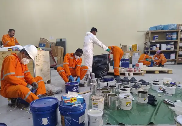 Crew sorting buckets and tins of materials in the workshop